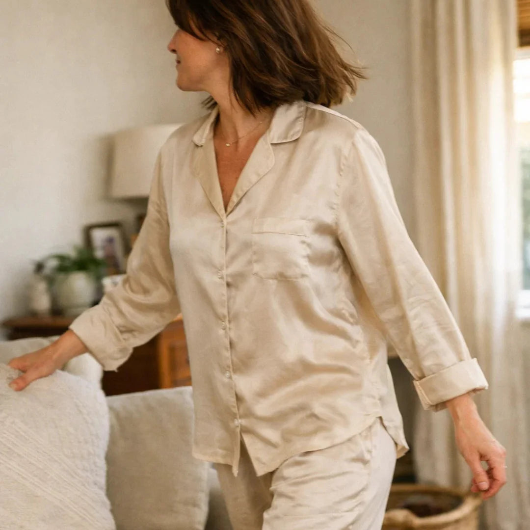 Woman wearing soft luxury sleepwear in a bedroom, representing perimenopause and menopause sleepwear for night sweats, comfort, and better rest.
