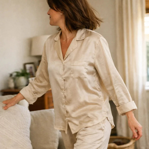 Woman wearing soft luxury sleepwear in a bedroom, representing perimenopause and menopause sleepwear for night sweats, comfort, and better rest.